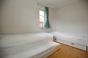 um quarto branco com 2 camas e uma janela em Likedeeler II Wohnung 02 em Boltenhagen