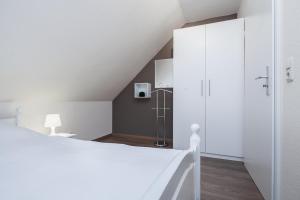 a bedroom with a white bed and a white cabinet at Papillon Wohnung 05-8 in Boltenhagen
