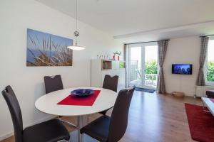 a dining room with a white table and chairs at Sünnslag Wohnung 039 in Boltenhagen