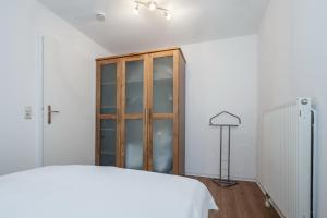 a bedroom with a white bed and a wooden cabinet at Papillon Wohnung 06-2 in Boltenhagen