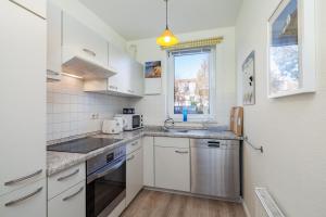 a kitchen with white cabinets and a sink and a window at Sünnslag Wohnung 097 in Boltenhagen