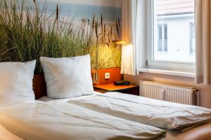 a bed with white sheets and pillows next to a window at Seebach Wohnung 18 in Boltenhagen