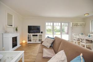 a living room with a couch and a tv and a table at Reethaus Am Mariannenweg 15b in Boltenhagen