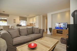 ein Wohnzimmer mit einem Sofa und einem TV in der Unterkunft Reethaus Am Mariannenweg 05b - Haus Baltic in Boltenhagen