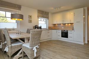 a kitchen with white cabinets and a wooden table and chairs at Reethaus Am Mariannenweg 05b - Haus Baltic in Boltenhagen