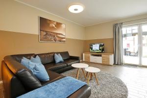 a living room with a leather couch and a tv at Reethaus Am Mariannenweg 20b in Boltenhagen