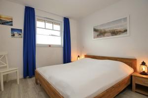 a bedroom with a bed with blue curtains and a window at Reethaus Am Mariannenweg 13b in Boltenhagen