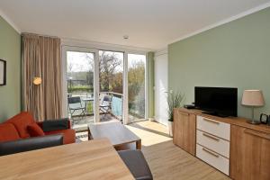 ein Wohnzimmer mit einem Sofa, einem TV und einem Tisch in der Unterkunft Villa Patricia Wohnung 12 in Kühlungsborn