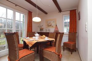 uma sala de jantar com mesa, cadeiras e janelas em Ferienhaus Hanni em Wittenbeck