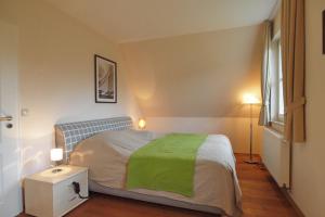 ein Schlafzimmer mit einem Bett mit einer grünen Decke darauf in der Unterkunft Ferienhaus Hanni in Wittenbeck