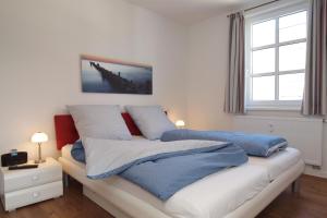 Schlafzimmer mit einem Bett mit blauer und weißer Bettwäsche in der Unterkunft Residenz von Flotow Wohnung 09 in Heiligendamm