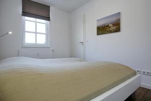 a white bedroom with a bed and a window at Residenz von Flotow Wohnung 10 in Heiligendamm