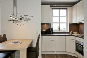 une cuisine avec des placards blancs et une table en bois dans l'établissement Residenz von Flotow Wohnung 12, à Heiligendamm
