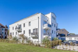 Un bâtiment blanc avec une voiture garée devant. dans l'établissement Residenz von Flotow Wohnung 13, à Heiligendamm