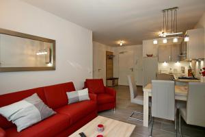 ein Wohnzimmer mit einem roten Sofa und einer Küche in der Unterkunft Linden-Palais Wohnung 06 in Heiligendamm
