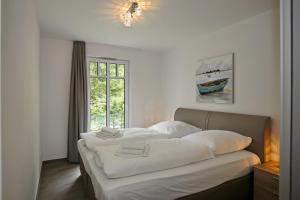 a bedroom with two beds with white sheets and a window at Linden-Palais Wohnung 06 in Heiligendamm