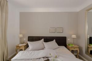 1 Schlafzimmer mit einem Bett mit weißer Bettwäsche und 2 Tischen in der Unterkunft Villa Sanddorn Wohnung 11 in Börgerende-Rethwisch