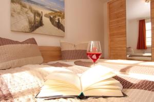 ein offenes Buch auf einem Bett mit einem Glas Wein in der Unterkunft Residenz von Flotow Wohnung 03 in Heiligendamm