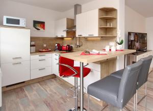 ハイリゲンダムにあるResidenz von Flotow Wohnung 05のキッチン(白いキャビネット、木製カウンター、赤い椅子付)