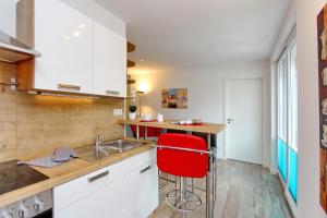 ハイリゲンダムにあるResidenz von Flotow Wohnung 05の白いキャビネットと赤いスツール付きのキッチン