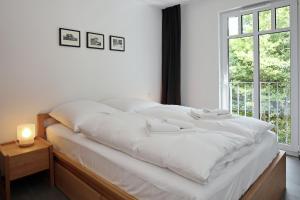 Cama blanca en habitación con ventana en Linden-Palais Wohnung 21, en Heiligendamm