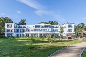 une grande maison blanche avec une pelouse devant elle dans l'établissement Linden-Palais Wohnung 21, à Heiligendamm