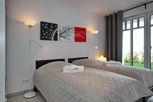 ハイリゲンダムにあるLinden-Palais Wohnung 04の白いベッドルーム(ベッド2台、窓付)