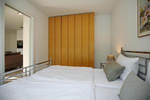 ハイリゲンダムにあるLinden-Palais Wohnung 39の白いベッド1台(木製ヘッドボード付)が備わるベッドルーム1室が備わります。