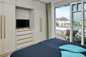 um quarto com uma cama, uma televisão e uma varanda em Linden-Palais Wohnung 34 em Heiligendamm