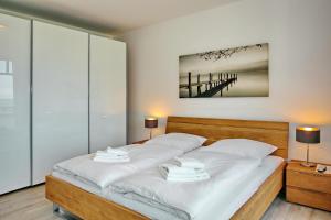 um quarto com uma cama com lençóis brancos e 2 candeeiros em Linden-Palais Wohnung 16 em Heiligendamm