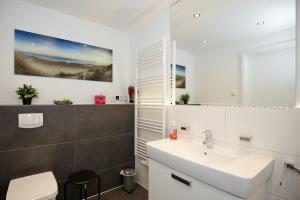 ein weißes Badezimmer mit einem Waschbecken und einem Spiegel in der Unterkunft Linden-Palais Wohnung 02 in Heiligendamm