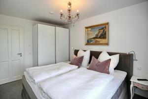 a large bed in a bedroom with a chandelier at Linden-Palais Wohnung 19 in Heiligendamm