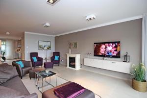 a living room with a couch and a tv on a wall at Linden-Palais Wohnung 37 in Heiligendamm