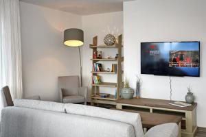 ein Wohnzimmer mit einem Sofa und einem TV an der Wand in der Unterkunft Linden-Palais Wohnung 14 in Heiligendamm