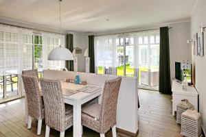 une salle à manger avec une table et des chaises blanches dans l'établissement Linden-Palais Wohnung 09, à Heiligendamm