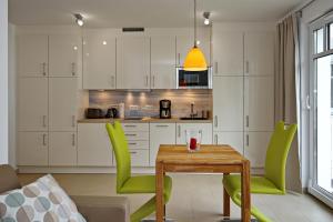 uma cozinha com uma mesa de madeira e cadeiras verdes em Linden-Palais Wohnung 27 em Heiligendamm