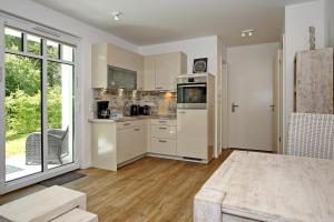 a kitchen with white cabinets and a large window at Linden-Palais Wohnung 08 in Heiligendamm