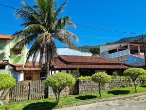 a house with a fence and a palm tree at Big Beach Casa Temporada in Mangaratiba