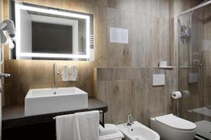a bathroom with a sink and a toilet and a mirror at Hotel Porta Nuova in Assisi
