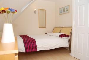 1 dormitorio con 1 cama y un jarrón con flores en Wigmore House en Great Barr