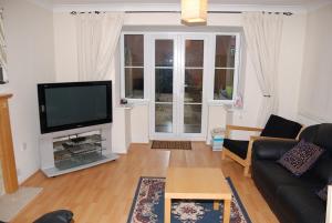 sala de estar con TV de pantalla plana y sofá en Wigmore House en Great Barr