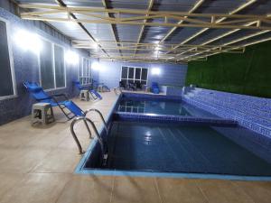 einen großen Pool mit blauen Stühlen in einem Zimmer in der Unterkunft Villa Salassel Al Jabal Al Akhdar فلة سلاسل الجبل الأخضر in Al ‘Ayn