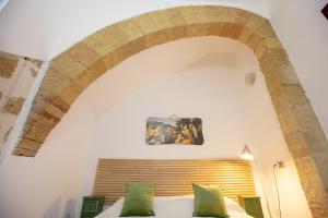 ein Schlafzimmer mit einem Torbogen über einem Bett mit grünen Kissen in der Unterkunft Alcova di relax in Castellammare del Golfo