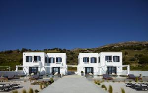 ein großes weißes Gebäude mit Stühlen davor in der Unterkunft Sereno Natu Villas in Skyros