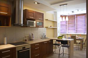a kitchen with wooden cabinets and a island with bar stools at PaulMarie Apartments on Prs. Stroiteley in Vitebsk