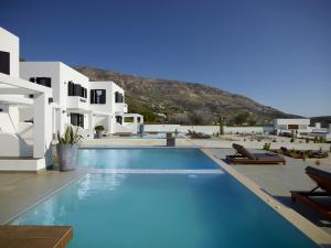 einen Pool mit weißen Gebäuden und einem Berg in der Unterkunft Sereno Natu Villas in Skyros