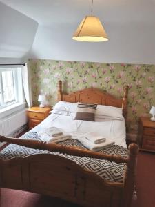 um quarto com uma cama de madeira com flores na parede em The Black Pig Public House em Staple
