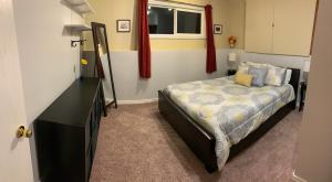 1 dormitorio con 1 cama con tocador y ventana en Newly Renovated Basement Suite!, en Lethbridge