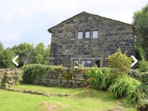 a stone house with two arrows pointing in front of it at Greave farmhouse 3-Bed Cottage in Todmorden in Todmorden