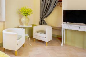 a living room with a tv and a white chair at La Chiocarella in Pienza